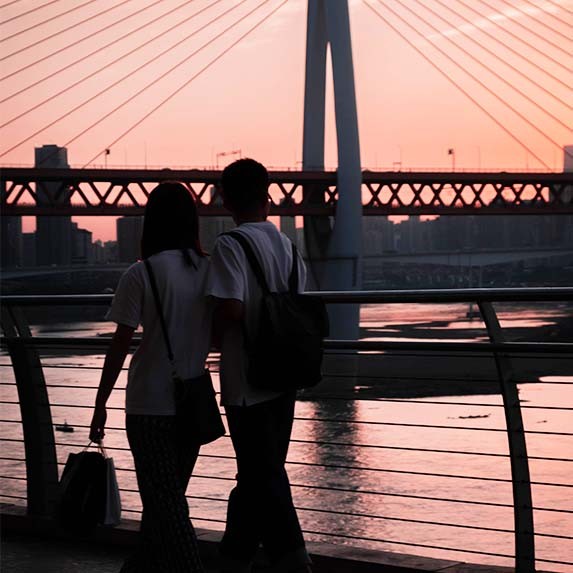 Cuplu tanar care se plimba sub apus.  Chaotianmen, districtul Yuzhong, Chongqing, China